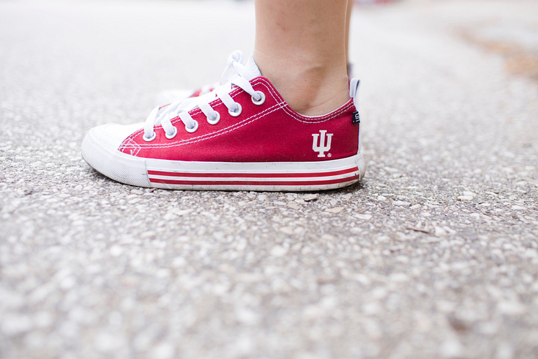 A person wearing a red shoe with an IU trident on it