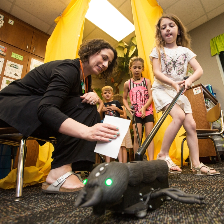 First-grade students prepare to use a push toy shaped like an ant.