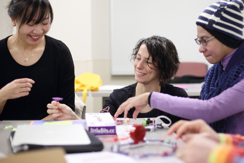 Kylie Peppler looks at crafts on a craft table with college students