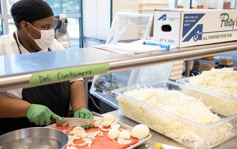 An IU Dining employee slices onions