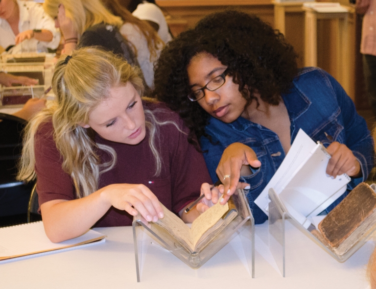 Two women look at a book in the Lilly Library.