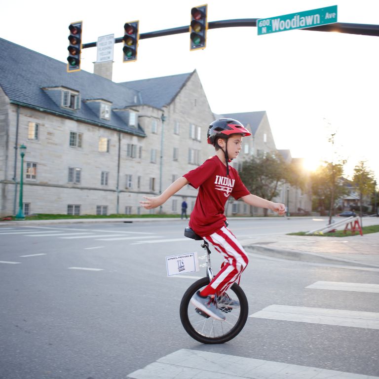 A young boy rides a unicycle. 