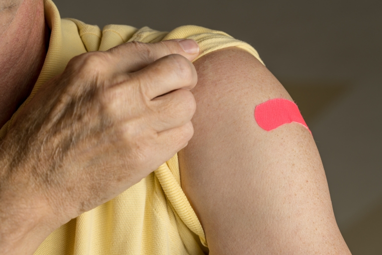 A person's arm featuring a bandage after a flu shot