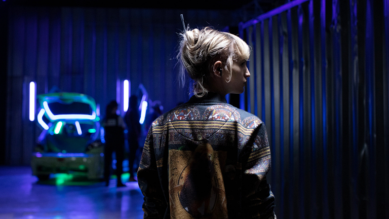 A woman wearing a jacket in a darkly lit room