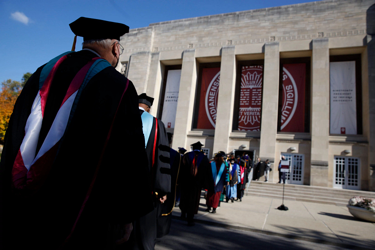 Procession of people in ceremonial robes walking into IU Auditorium