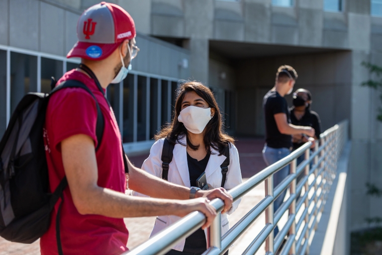 Students talk on the IUPUI campus while wearing face coverings.