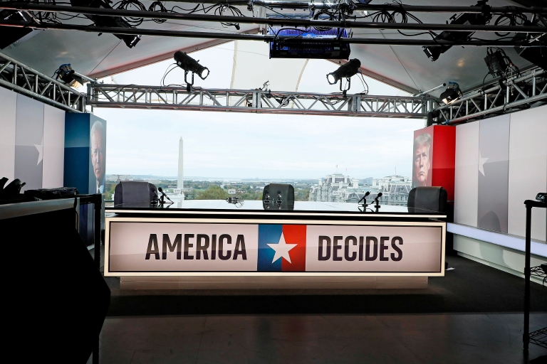 A TV news set with a chyron that reads 'American Decides'