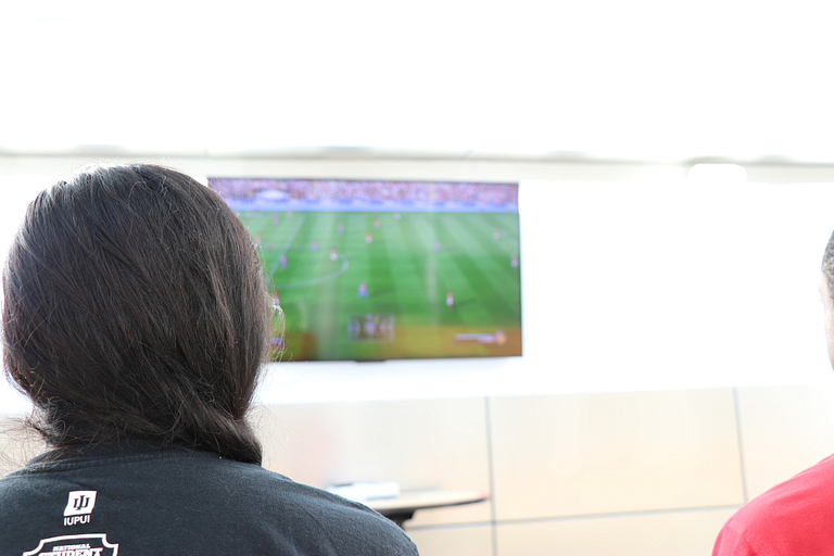 Student plays a soccer video game on a large television.