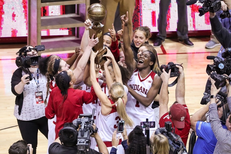 The IU women's basketball team gathers to hold up their WNIT championship trophy.