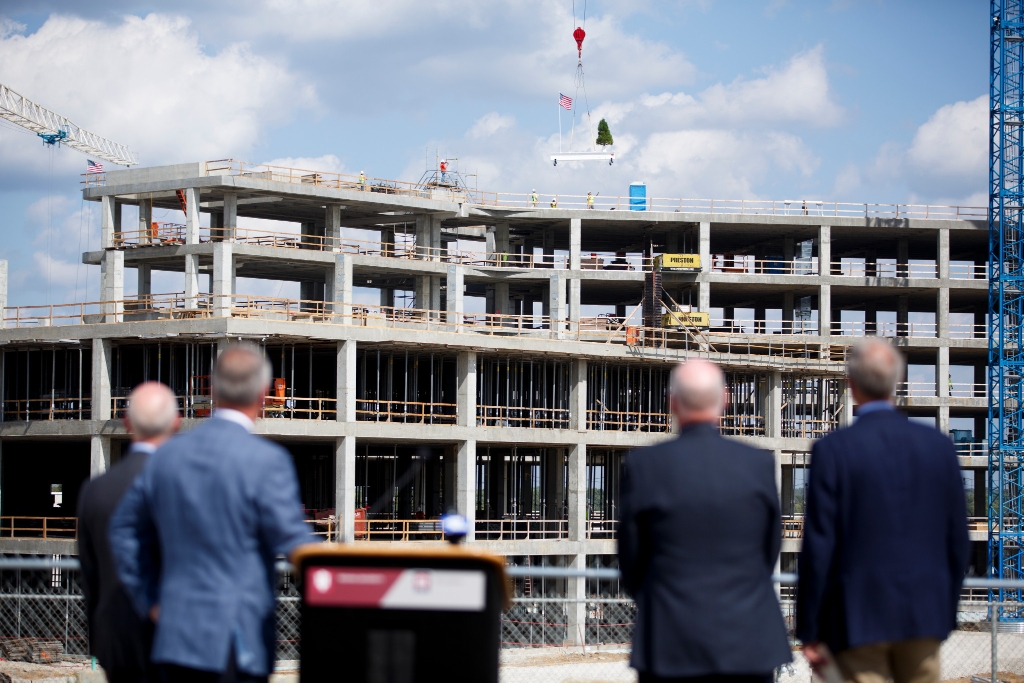 Officials look on as the final beam is placed atop the Regional Academic Health Center