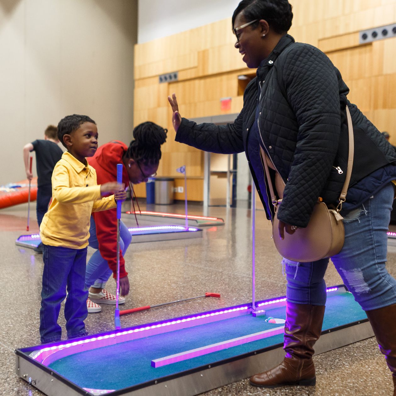 A kid and his family member plays LED putt putt during JagFest.