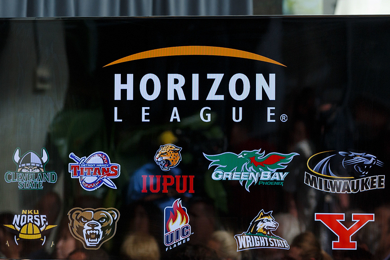 A screen shows logos of Horizon League schools.