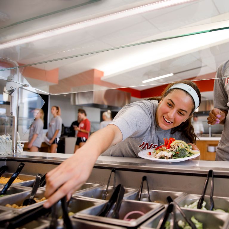 A member of the women's soccer team fills her plate at the Tobias Nutrition Center