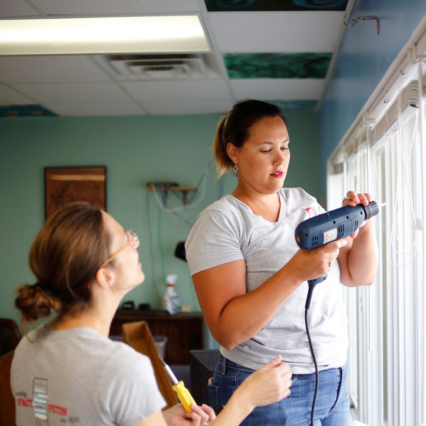 Librarians use a drill to hang curtains