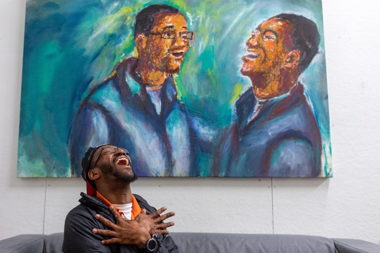 Herron School of Art student Johnson Simon laughs in front of one of his paintings. 
