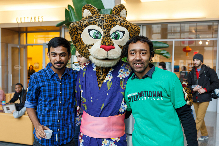 Two male students pose for a photo with mascot Jazzy at the International Festival