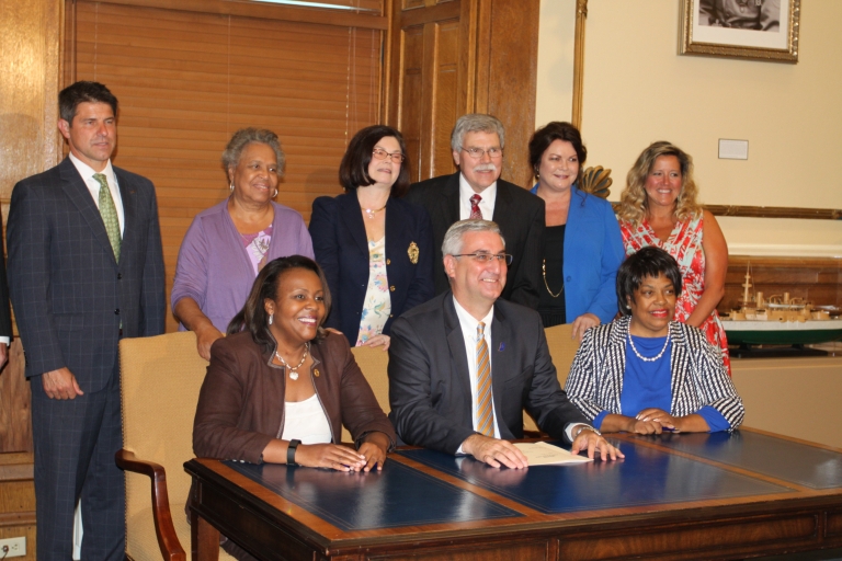 Governor Eric Holcomb, state Senator Jean Breaux, and Michael and Lisa Patchner at the bill signing.