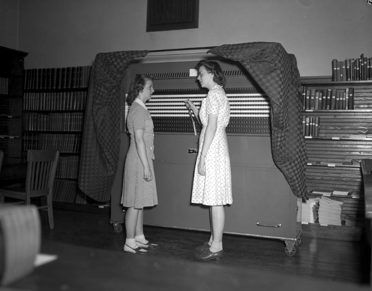 Women stand by a voting machine