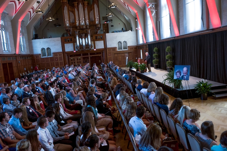 Dennis Groth stands behind a podium talking to Cox Scholars.