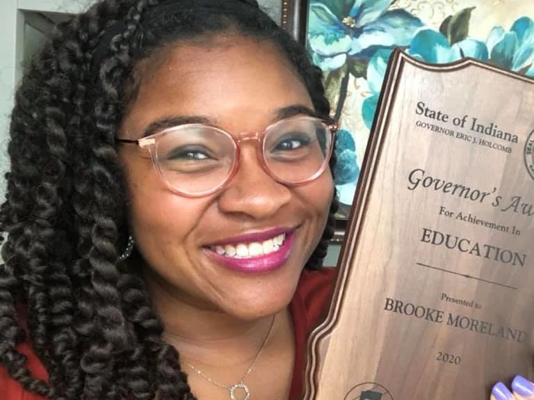 a woman holds up an award