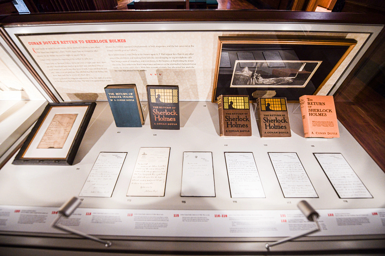 A display case features Sherlock Holmes books and letters from Arthur Conan Doyle