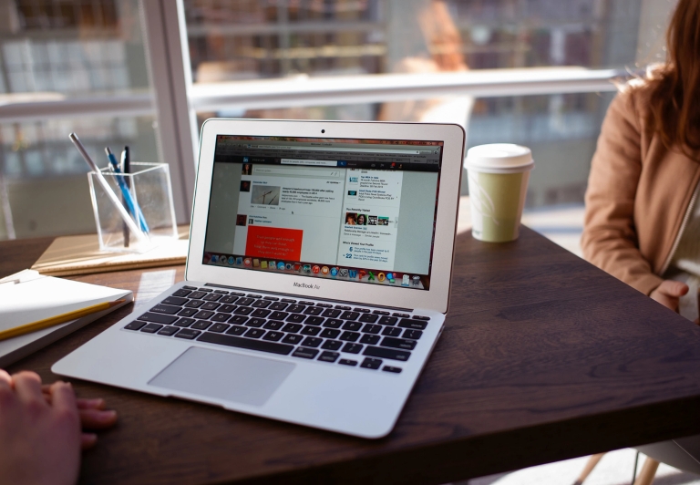 A laptop computer showing a LinkedIn Learning page on the screen rests on a table near two people.