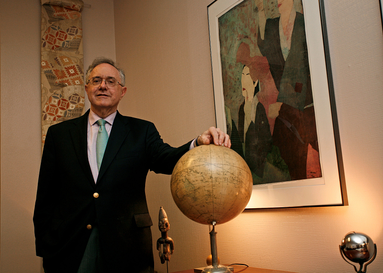 Patrick O'Meara stands with his hand on a globe.