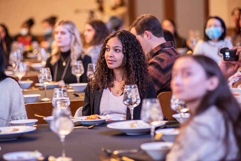 A woman sits at a table with other students.