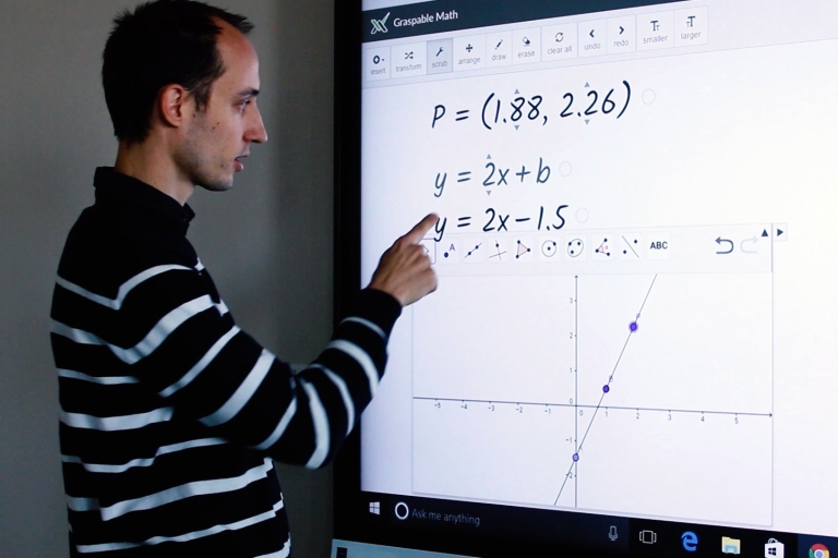 man touches large display screen that shows several algebraic equations