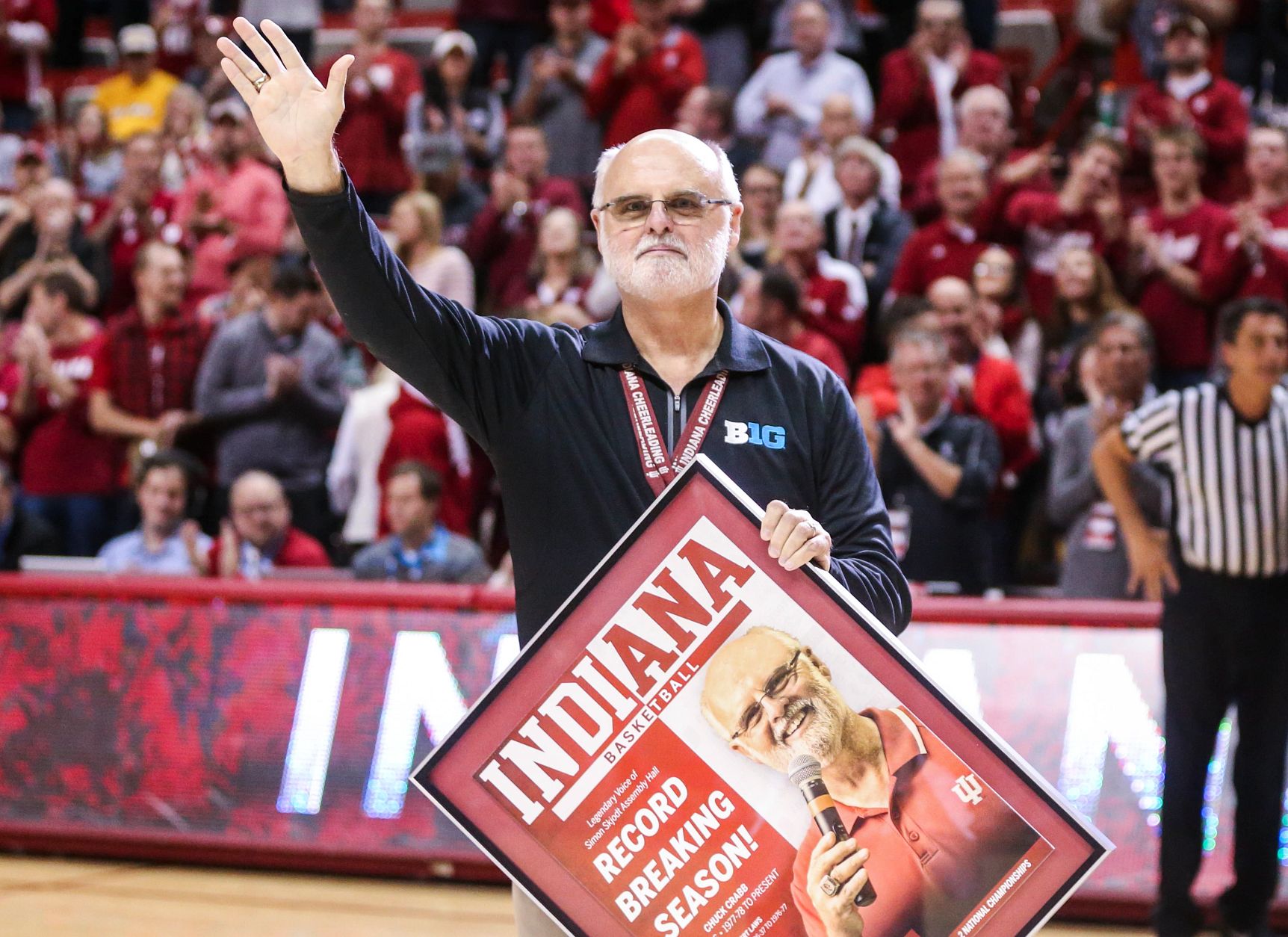 Chuck Crabb waves to a crowd as he holds a framed poster of himself
