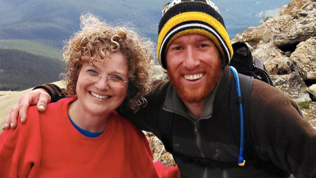 Idie Kesner poses on a mountainside next to a man who has his arm around her shoulder