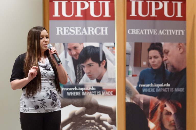 Autumn Fox gives her project pitch onstage in front of posters.