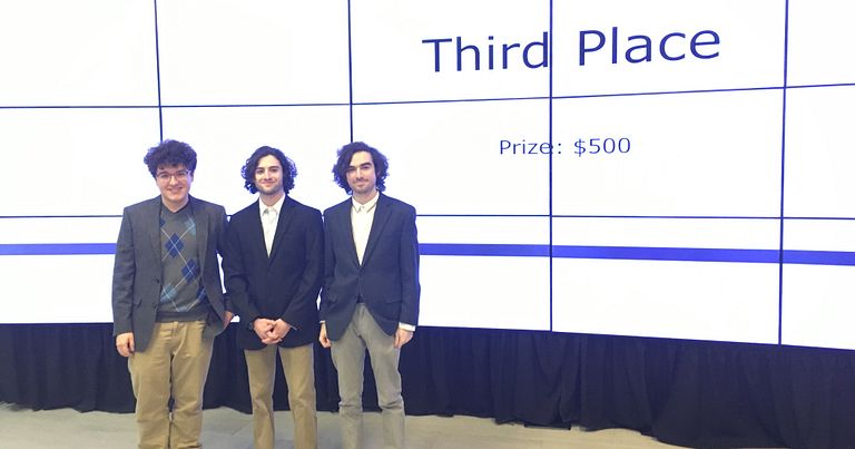 Co-founders of Eqlsr stand in front of a screen that reads Third Place Prize: $500