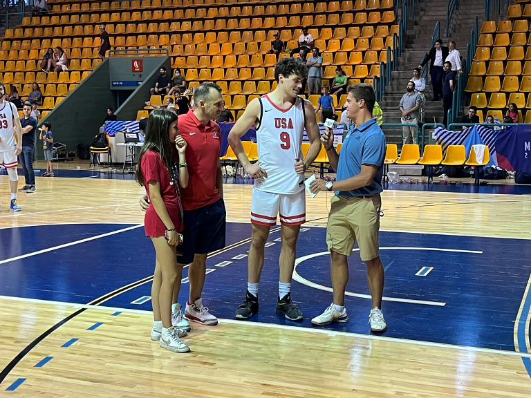 A reporter interviews a basketball player on the court.
