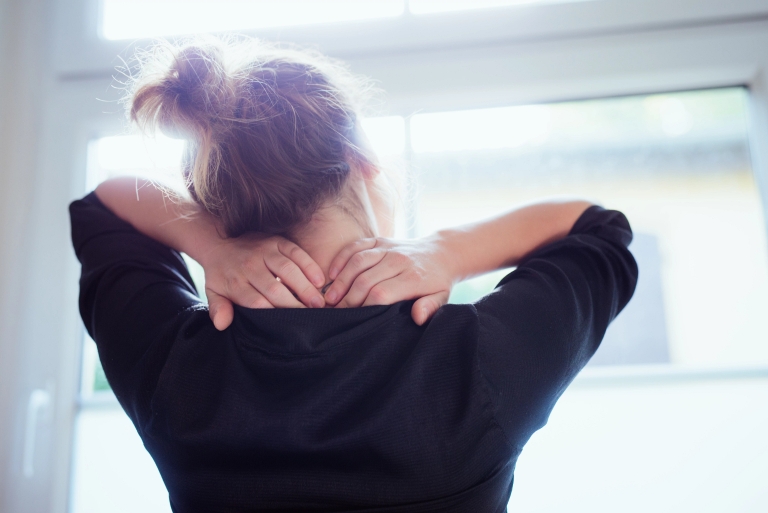 woman grabs behind her head in stress