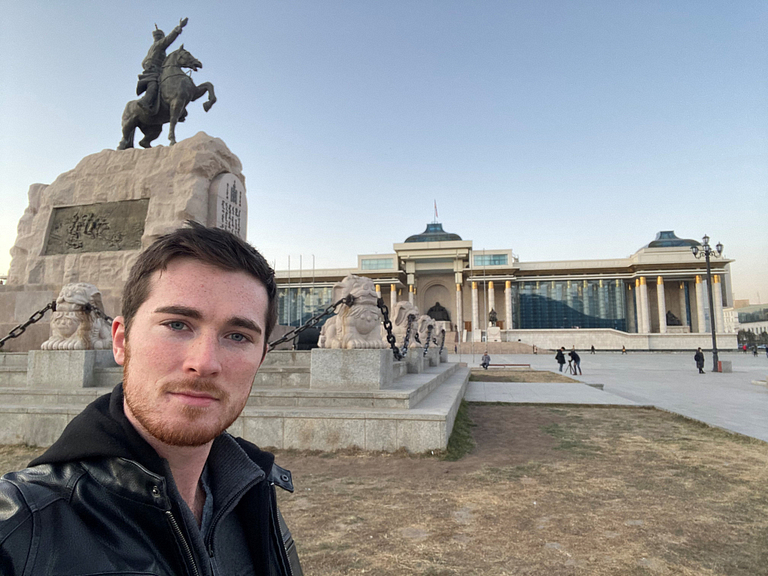 Brandon Boynton standing in front of Mongolia's Government Palace