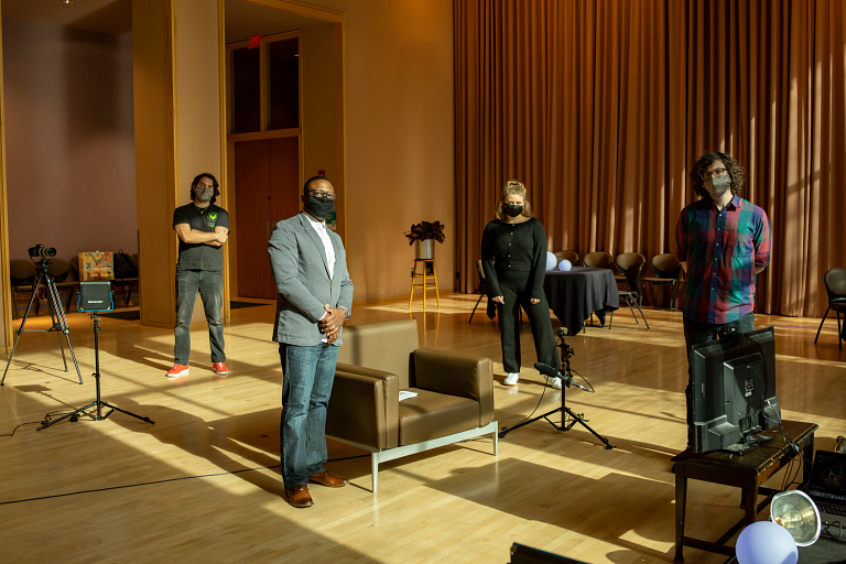 Group of people pose in front of film set while wearing masks