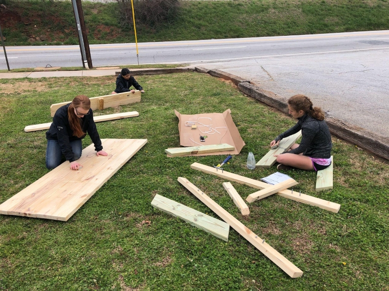 Students assemble a picnic table for workers