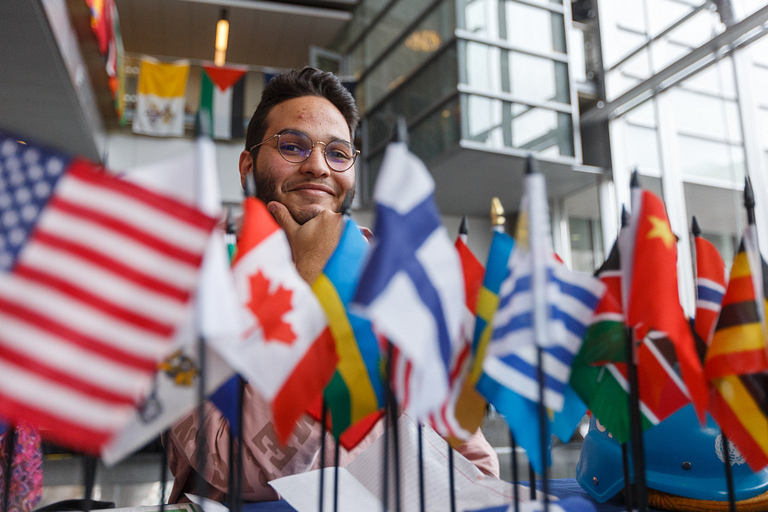 a student poses behind a row of flags sitting at a table