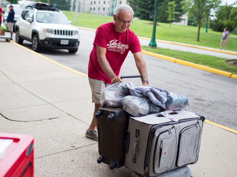 A man pushes a cart into a residence all on move-in day.