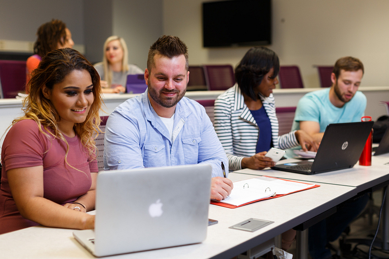 Students work on a computer in a lecture hall.