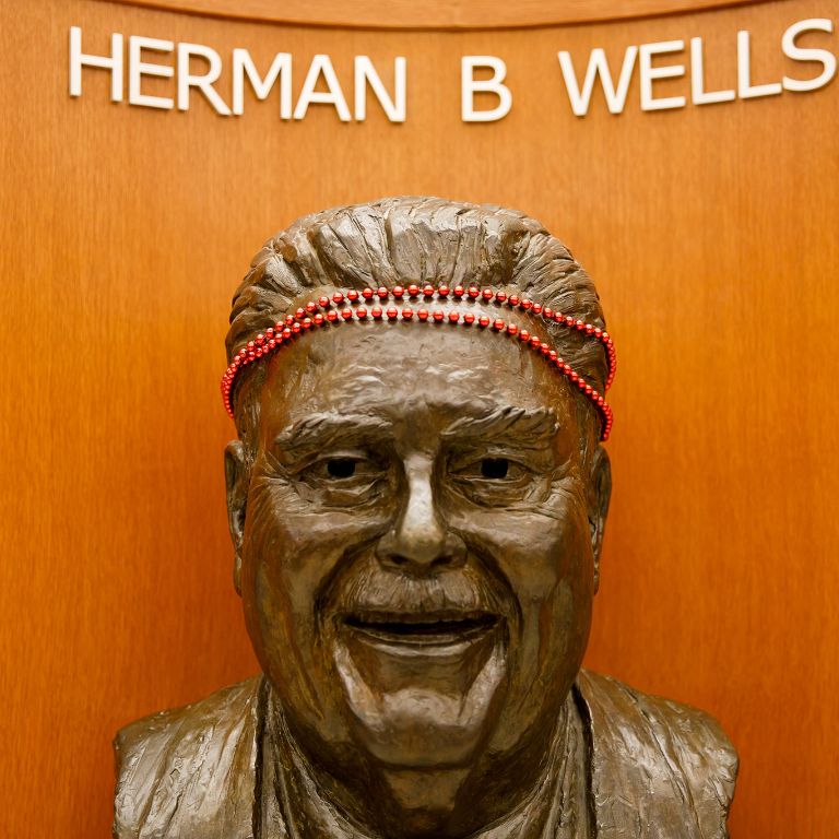 A bust of Herman B Wells with beads on its head