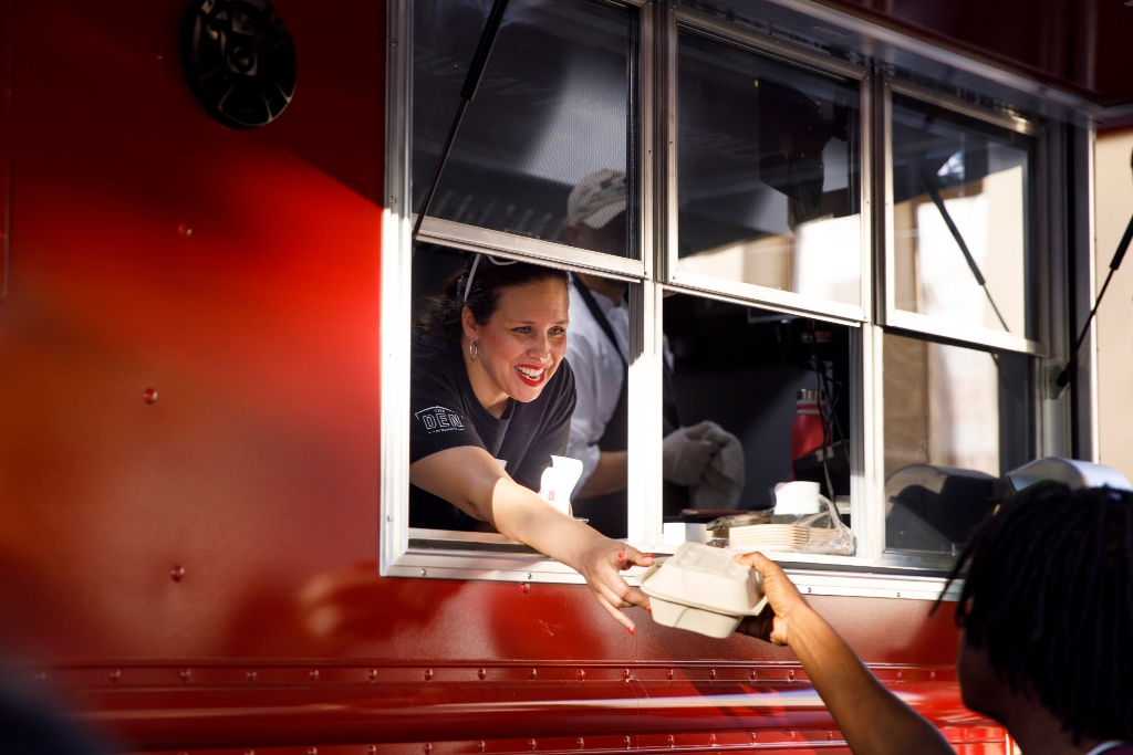 A woman serves food out of a food truck