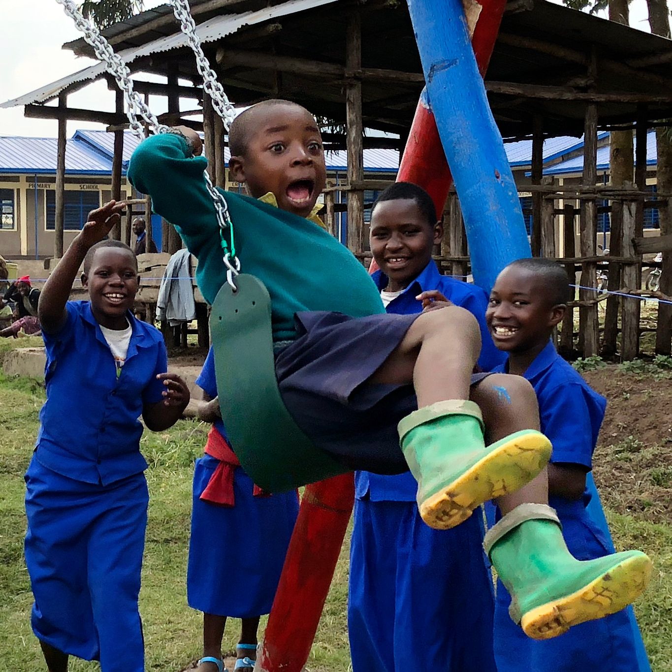 Students at Nyabitsinde School swing on the school's newly built playground