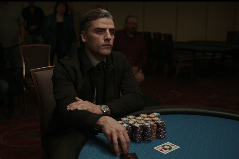 A man sits with poker chips and cards at a table