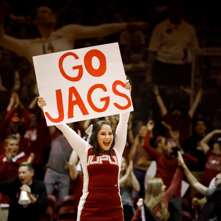 A cheerleader holds up a sign that says 'Go Jags'
