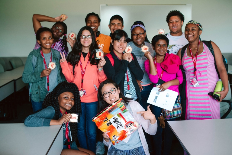 A group of high school students pose with their Chinese-language instructor in a classroom.