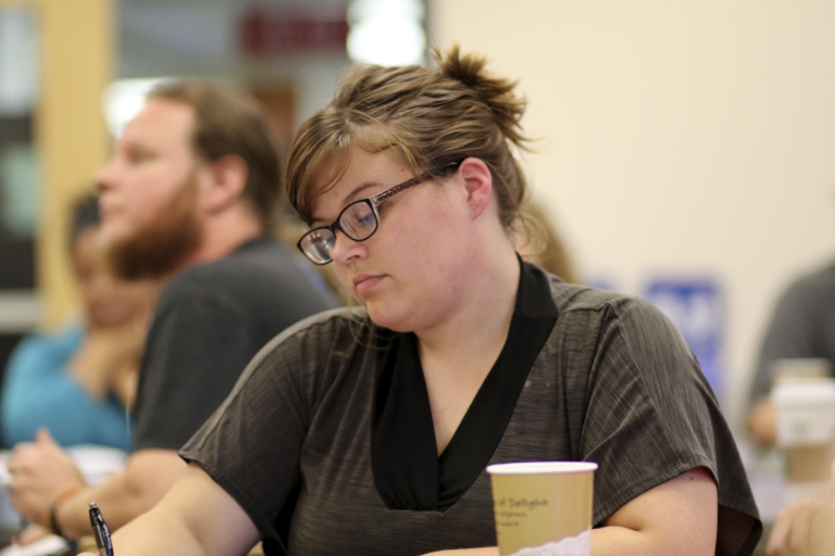 A female student writes at a table.