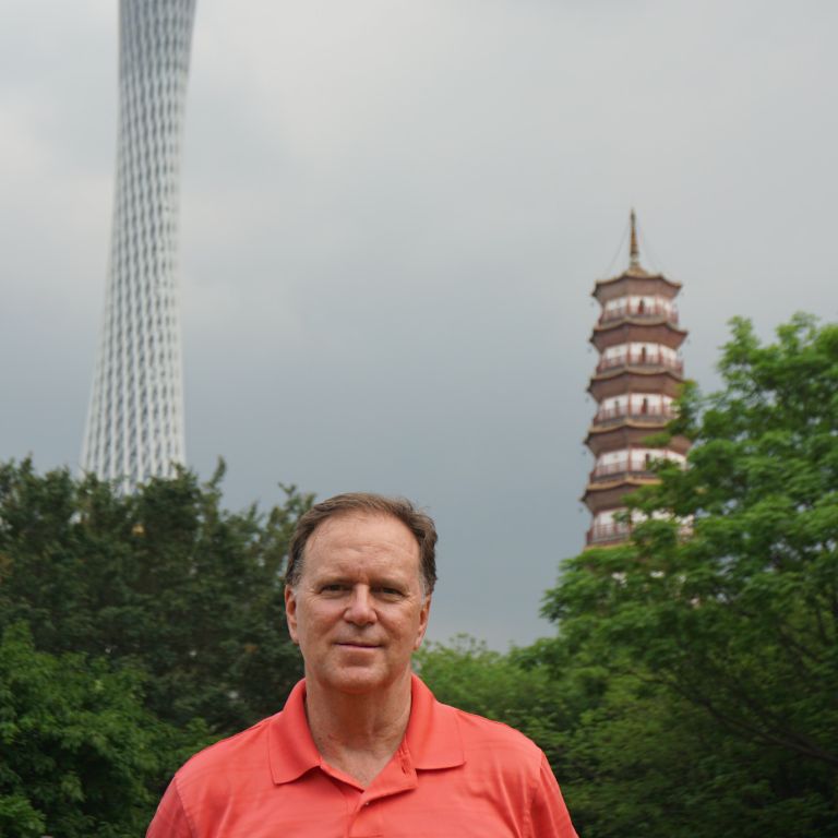 Ian McIntosh stands in front of buildings.