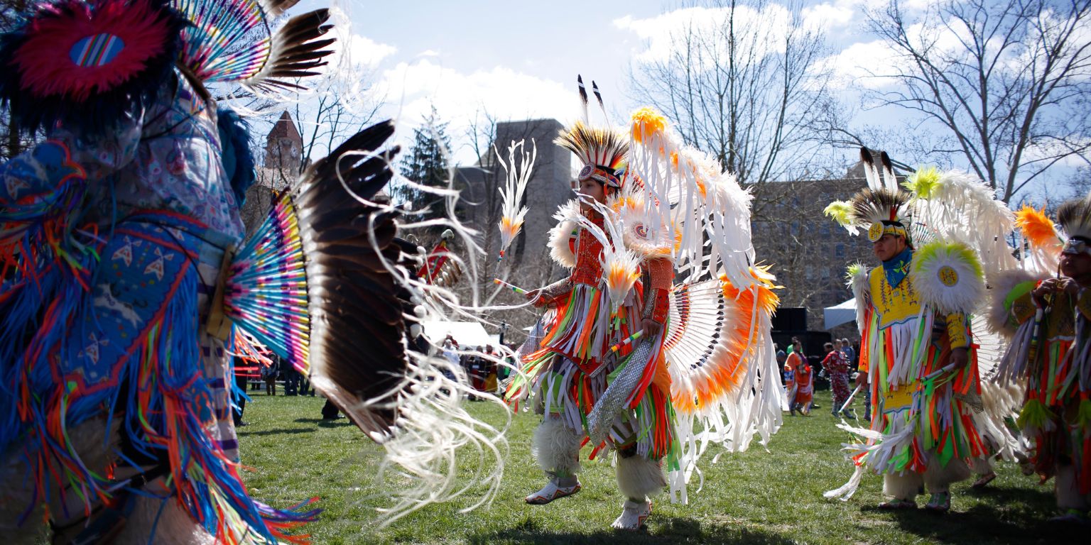 Three men dance in Dunn Meadow during IU's powwow